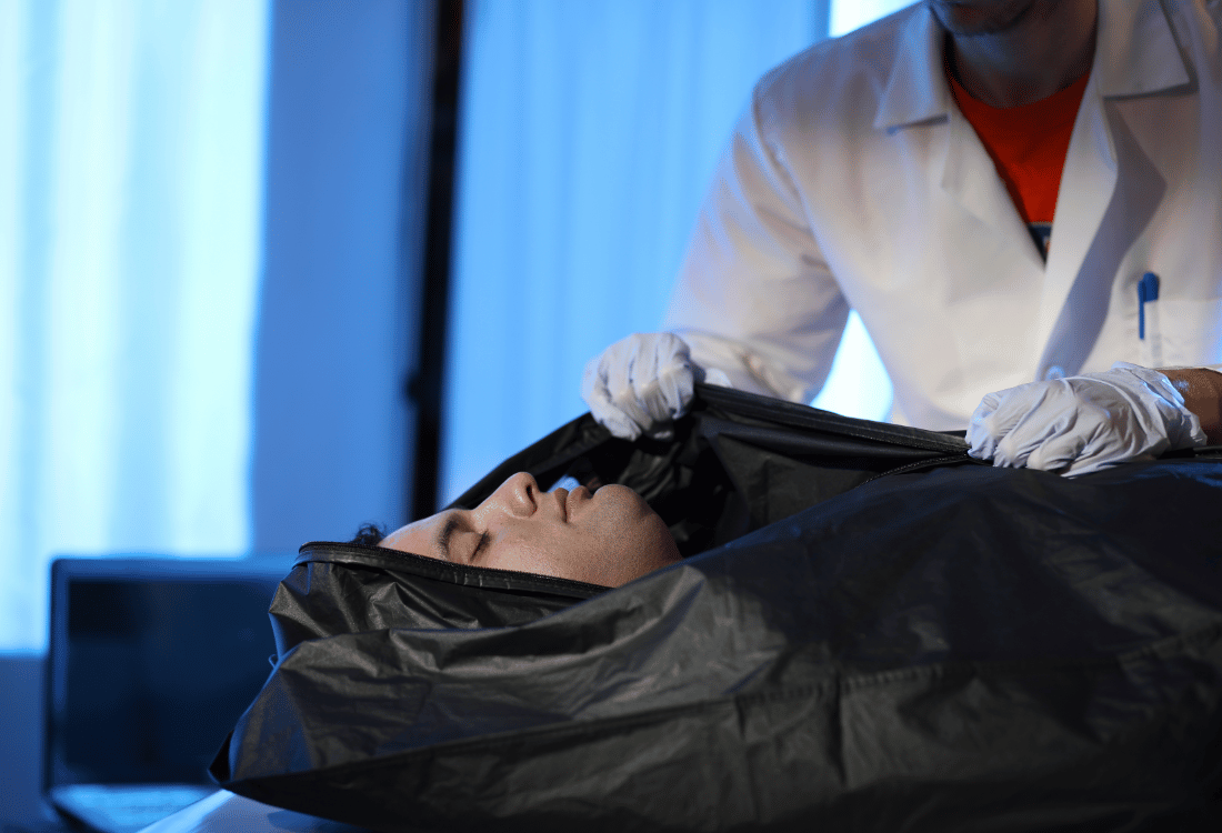 Medical examiner with a corpse in a morgue stocked up with the three types of body bags you need for your hospital. 